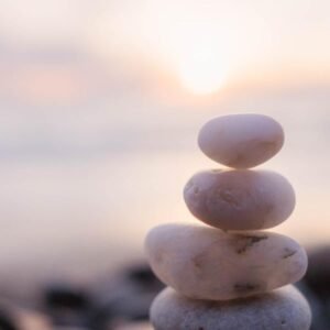 Stacked white pebbles on a beach at sunrise, symbolizing calm and balance